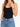A woman wearing a black tank top and high-waisted blue jeans, showcasing a colorful beaded bracelet on her wrist.