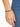 A close-up of a hand wearing a beaded bracelet featuring dark blue and gold accents against denim fabric.