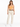 A woman stands confidently in a fitted orange crop top, beige high-waisted pants, and white sneakers.