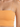 Close-up of a cropped top in a soft orange hue, featuring thin spaghetti straps and a ribbed texture.