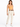 A woman stands in a fitted orange crop top and cream-colored high-waisted pants, paired with white sneakers.