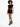 A model poses in a black cropped top and stylish black shorts with unique cut-out details, paired with combat boots.