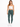 A model wearing a fitted white crop top and green leggings, paired with white sneakers against a plain background.