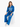 A model sits wearing vibrant blue pants and a matching hoodie with a graphic design, paired with white sneakers.