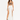 A model poses in a white skirt with high slits, paired with a brown crop top and black strappy heels.