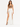 A model poses in a white skirt with high slits, paired with a brown crop top and black strappy heels.