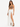 A model poses in a flowing white skirt with high slits, paired with a brown crop top and black heels.