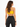 A woman with long, wavy hair wears a yellow crop top and black high-waisted leggings, viewed from the back.