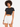 A young woman with curly hair wears a fitted black top and white high-waisted shorts, posing confidently.