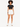 A model stands confidently in a fitted black crop top and white high-waisted shorts, paired with white sneakers.
