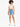 A person with curly hair wearing a beige crop top and distressed denim shorts, paired with white sneakers.