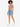 A model with curly hair wears a fitted brown crop top and distressed denim shorts, paired with white sneakers.