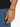 A close-up of a hand wearing a beaded bracelet with a mix of gray and black stones, resting on denim.