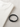 A black leather bracelet with a sleek clasp rests beside a folded white shirt on a textured surface.