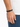 A close-up of a hand wearing a black beaded bracelet with a sleek clasp, set against a light background.