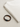 A black and brown bracelet rests beside a folded cream-colored sweatshirt on a textured surface.