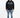 A man stands wearing a black hoodie with graphic text, paired with light blue jeans and stylish sneakers.