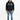 A man stands wearing a black hoodie with graphic text, paired with light blue jeans and stylish sneakers.