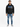 A man stands wearing a black hoodie with graphic text, paired with light blue jeans and stylish sneakers.