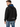 A man wearing a black sweatshirt with blue lettering on the hood and text on the back, paired with blue jeans.