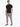 A man stands confidently in a fitted black short-sleeve shirt paired with light gray cargo pants and stylish sneakers.