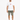 A man stands wearing a white graphic t-shirt and olive green distressed shorts, paired with white sneakers.