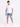 A man stands wearing a fitted white short-sleeve t-shirt paired with light blue denim shorts and white sneakers.
