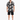 A man stands wearing a short-sleeve button shirt with a black and white graphic print, paired with black shorts.