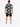 A man wearing a short-sleeve button shirt with a bold graphic print, paired with black shorts and sneakers.
