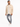 A man stands wearing a textured beige shirt jacket over a white t-shirt, paired with distressed gray jeans and white...