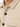 Close-up of a textured beige top featuring a patterned fabric, black buttons, and a classic collar design.