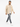 A man walks confidently in a beige button-up top, paired with distressed gray jeans and white sneakers.