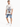 A man stands wearing a graphic t-shirt and denim shorts, paired with white sneakers, showcasing a casual look.