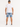A man wearing rolled denim shorts and a white t-shirt, standing with his back to the camera.