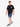 A man walks confidently in denim shorts, paired with a black t-shirt and stylish sneakers.