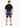 A man stands with his back to the camera, wearing rolled denim shorts and a black t-shirt.