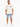 A man stands wearing a light-colored oversized t-shirt and distressed denim shorts, paired with white sneakers.