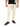 Light-colored jogger pants with side zippers, paired with a black t-shirt and black sneakers.