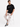 A man sits on a stool wearing a black t-shirt with white text, paired with light cargo pants and sneakers.