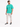 A man stands wearing a teal t-shirt with a motivational quote, paired with light cargo pants and black sneakers.