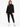 A woman stands confidently in a black, oversized sweatshirt paired with matching joggers and white sneakers.