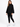 A woman stands confidently in a black oversized sweatshirt paired with matching joggers and white sneakers.