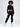 A model poses in a cropped black sweatshirt and matching jogger pants, showcasing a casual streetwear style.