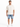 A man stands wearing a loose-fitting beige t-shirt and distressed denim shorts, paired with white sneakers.
