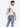 A man wearing a white graphic t-shirt and light blue distressed jeans, posing with his back to the camera.