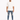 A man stands confidently in distressed blue jeans, paired with a loose-fitting white t-shirt and white sneakers.