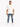 A man stands confidently in distressed blue jeans, paired with a loose-fitting white t-shirt and white sneakers.