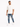 A man wearing a loose white t-shirt and distressed blue jeans, paired with white sneakers, walking confidently.