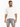 A man stands wearing a loose-fitting white t-shirt and gray distressed denim shorts with frayed edges.