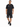 A man stands wearing a black graphic t-shirt and distressed black shorts, paired with black athletic shoes.